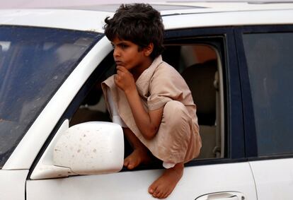 Un niño sentado en un coche mientras mira a los camellos.