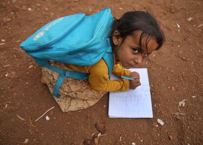 Una niña siria escribe en su cuaderno junto al lugar donde se encuentra ubicada la escuela.