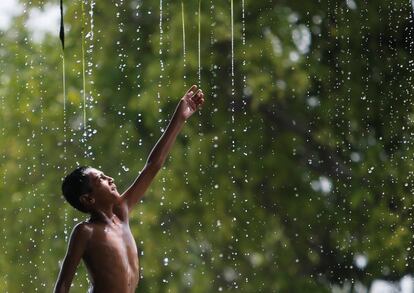 Un niño se refresca bajo una fuente de agua en un día caluroso en Nueva Delhi (India).