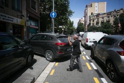 Dídac, mecánico de un taller de la calle de València de Barcelona, ayuda a maniobrar a un cliente sobre el nuevo carril bici.