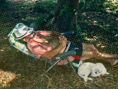 Un hombre realiza una siesta debajo de una higuera junto a su mascota./ ÓSCAR CORRAL (EL PAÍS).