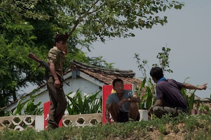 Um soldado norte-coreano fala com dois agricultores, cerca de Sinuiju.