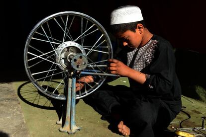 Un niño afgano repara la rueda de una bicicleta en una tienda de Kandahar.