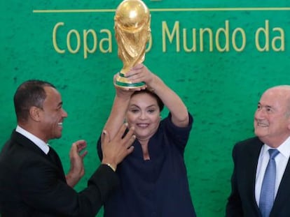 A presidenta Dilma Rousseff eleva o trof&eacute;u ao lado do ex-jogador Cafu e de Joseph Blatter nesta segunda-feira.