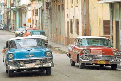 Coches antiguos en La Habana Vieja (dos Chevrolet, uno azul, probablemente de 1956, y otro rojo modelo Bel Air de 1958).