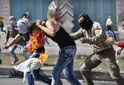 El joven palestino intenta quitarse la ropa que arde sobre su cuerpo.