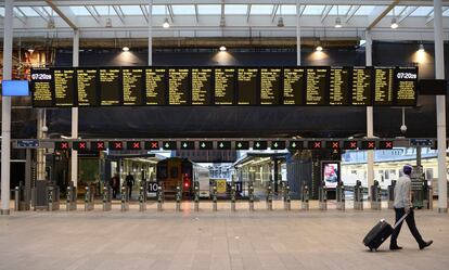 Un viajero solitario camina por la estación de London Bridge en Londres. Los paneles informativos muestran que el transporte ferroviario ha sido cancelado.