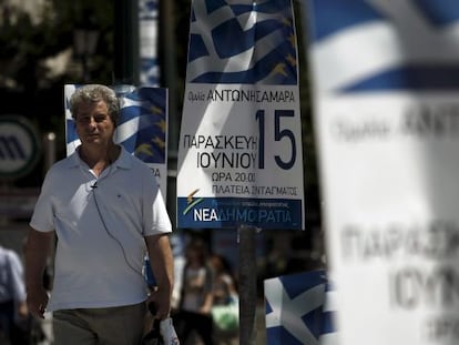 Un hombre camina junto a varios carteles del partido conservador griego Nueva Democracia (ND), hoy en Atenas.