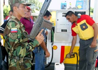 Un soldado vigila el reparto de combustible en una gasolinera e Maracaibo.