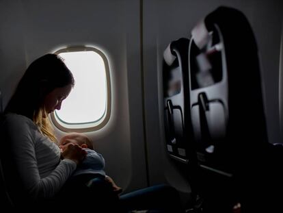 Una mujer amamanta a su bebé en un avión.