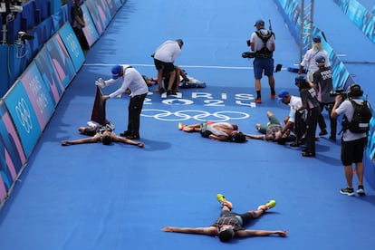 Varios triatletas tumbados tras cruzar la línea de meta de la prueba de triatlón masculino.
