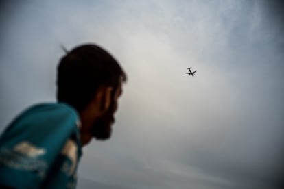 En 2015, tras décadas de guerras, bombardeos y violencia, Mustafá Manzuri (29 años) y gran parte de su familia decidieron huir de Afganistán. Su éxodo comenzó al salir de su país rumbo a Irán, adonde llegaron en 2016. Una vez allí, cruzaron las montañas que unen la república islámica con Turquía y, llegados a la costa turca, subieron a una de las balsas que cruzan el mar Egeo. En 2019, lograron desembarcar en la isla griega de Lesbos. En la imagen, Manzuri observa el paso de un avión a orillas del mar Egeo, que une la costa turca con Lesbos, donde vivió casi dos años junto a su familia, primero en el campo de refugiados de Moria y luego en el de Kara Tepe. Durante ese tiempo, estuvieron a la espera de una respuesta de sus solicitudes de asilo para poder ingresar en Alemania.