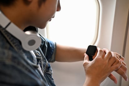 Un joven consulta su reloj en un vuelo.