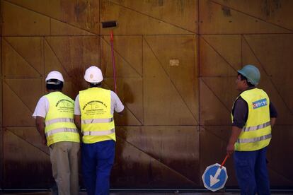 Varios obreros de la construcción pintan una chapa en una obra en el centro de Madrid.