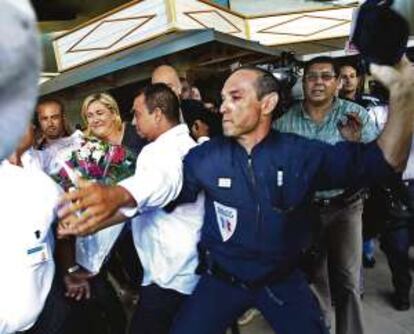 La dirigente ultraderechista Marine Le Pen, protegida por la policía, es abucheada a su llegada al aeropuerto de Reunión.
