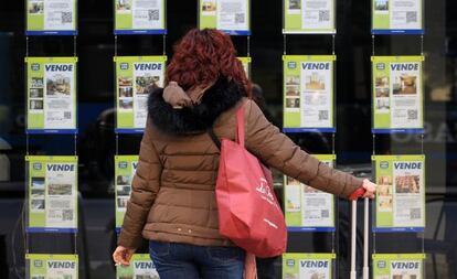 Una mujer examina los anuncios de venta de pisos en una oficina inmobiliaria de Madrid.  