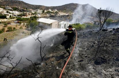 Un bombero extingue un fuego en Ática, a las afueras de Atenas. Este domingo se han registrado algunos incendios en las cercanías de la capital griega sin que se reporten mayores daños.