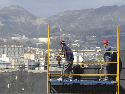 Unos obreros, en el andamio de una obra, en Ceuta.