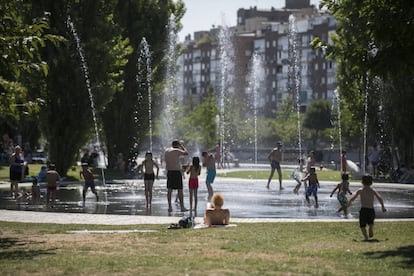 People cool down running through a water fountain in Madrid Rio park.