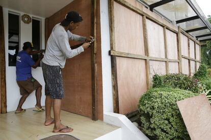 Dos trabajadores aseguran las ventanas de un hotel con láminas de madera contrachapada como precaución ante la llegada del tifón Mangkhut a Filipinas.