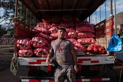 Jorge Latorre posa en su camión de trabajo cargado con sacos de papas y habas.