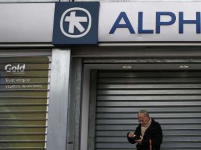 Ciudadanos, delante de una sucursal de Alpha Bank en Atenas.