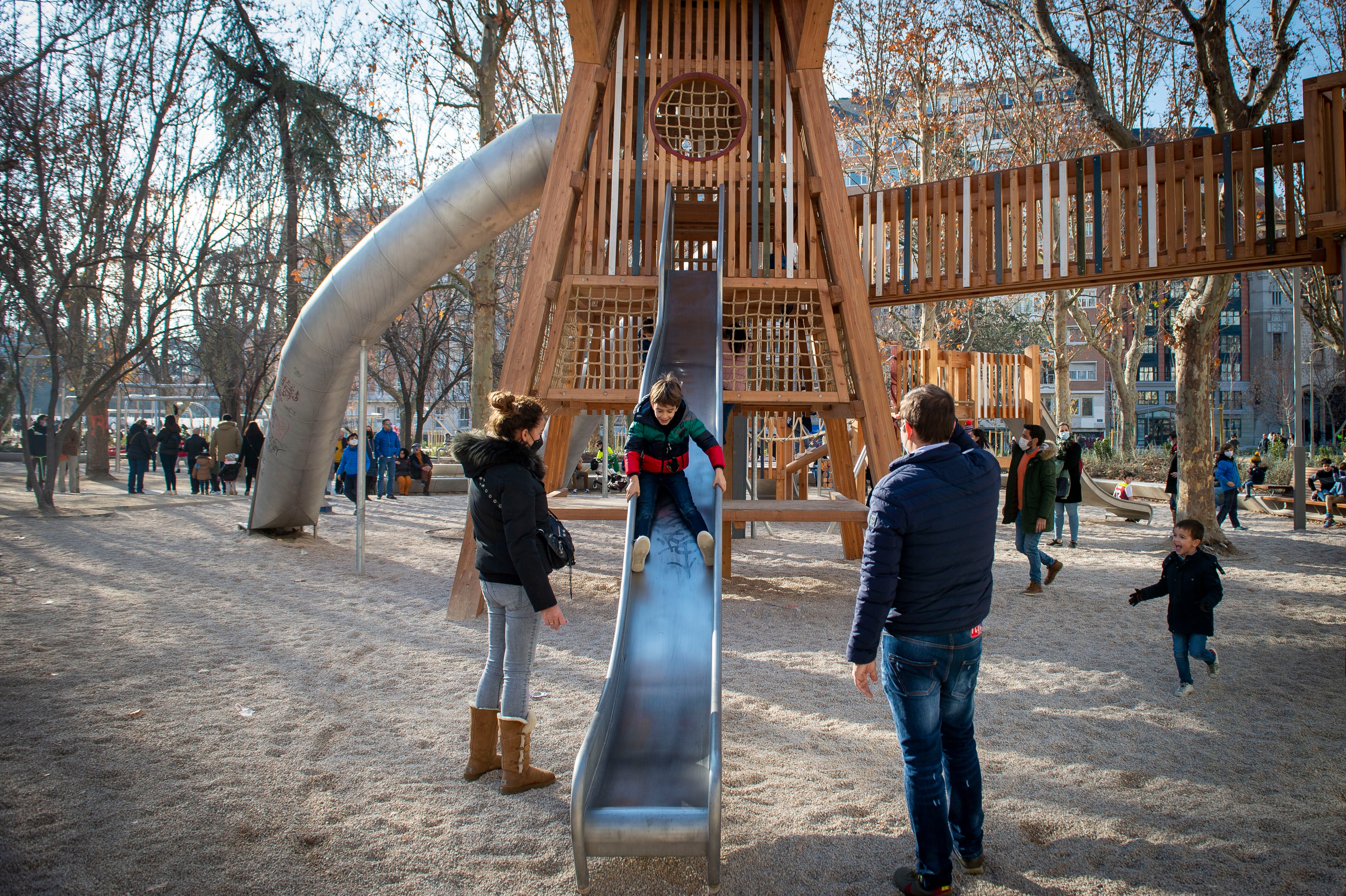 Unos padres jugando con sus hijos en un parque infantil.