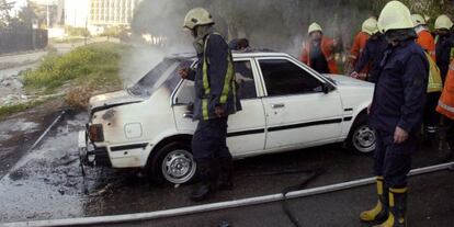 Bomberos observan un coche incendiado ayer en el centro de Damasco.