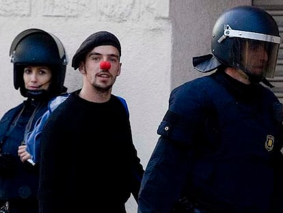 Dos <i>mossos d'esquadra</i> acompañan a uno de los <i>okupas</i> de Can Ricart.