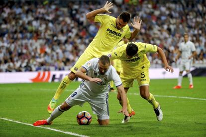 El delantero francés del Real Madrid Karim Benzema (c) cae entre Víctor Ruiz y el argentino Mateo Musacchio (d), del Villarreal, durante el partido de la quinta jornada de la Liga de Primera División que se juega en el estadio Santiago Bernabéu.