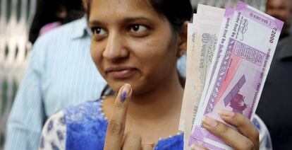 Una mujer muestra su dedo te&ntilde;ido con tinta permanente despu&eacute;s de cambiar por otros nuevos los billetes retirados de la circulaci&oacute;n la semana pasada, en una sucursal bancaria en Bhopal, el 16 de noviembre de 2016. 