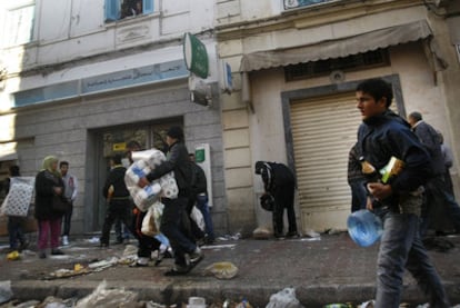 Varias personas se llevan comida y enseres de un almacén destruido ayer en la ciudad de Túnez.