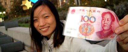 Una mujer sujeta un billete de 100 yuanes. 
