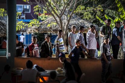 Migrantes y refugiados se alinean de manera ordenada para recoger alimentos en un refugio en México.