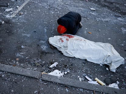 Un hombre junto al cadáver de un familiar muerto en el bombardeo a un edificio residencial en Kiev, este jueves.