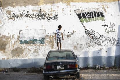 Un niño juega sobre un coche a las puertas de un colegio en el barrio de Sooq Jumaa, en Trípoli