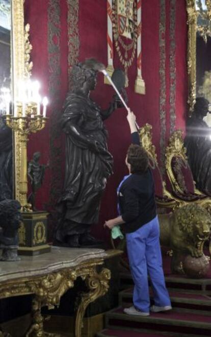 Una trabajadora limpia una de las estatuas del salón del trono del Palacio Real.