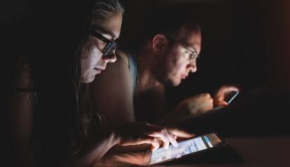 Una pareja lee en sus dispositivos móviles.
