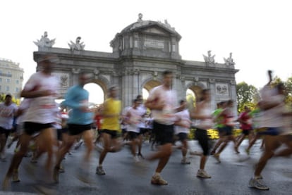 Un grupo de corredores rodea la Puerta de Alcalá durante el recorrido de 10 kilómetros de la carrera popular 'Madrid corre por Madrid'.