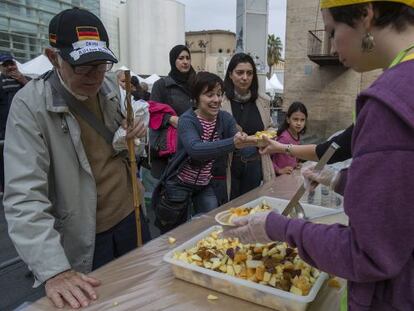 Un grupo de voluntarios reparte alimentos en El Gran Dinar de Barcelona, una feria para impulsar la conciencia alimentaria.