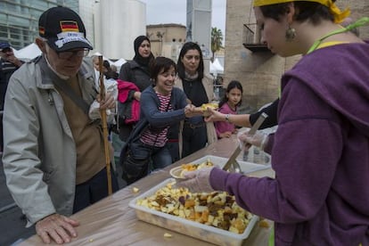 Un grupo de voluntarios reparte alimentos en El Gran Dinar de Barcelona, una feria para impulsar la conciencia alimentaria.