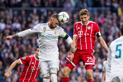 El defensa del Real Madrid Sergio Ramos (i) despeja de cabeza junto a Thomas Muller, del Bayern Múnich.