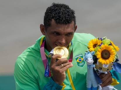 Isaquias Queiroz morde sua medalha de ouro na canoagem.