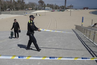 Un agente de la Guardia de Barcelona cierra el acceso a una playa de Barcelona, el 15 de marzo.