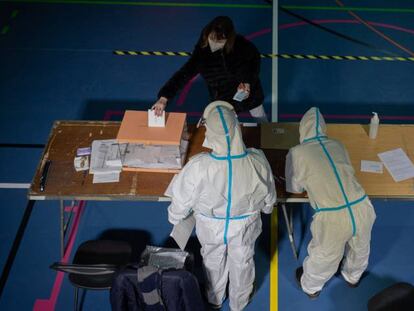 Miembros de las mesas protegidos con Equipos de Protección Individual (EPI) a la llegada de uno de los electores contagiados