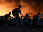 Refugees and migrants carry their belongings as they flee from a fire burning at the Moria camp, on the island of Lesbos, Greece, September 9, 2020. REUTERS/Elias Marcou