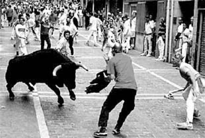 Un joven ataviado con un casco vikingo cita imprudentemente a un toro en la calle Estafeta.