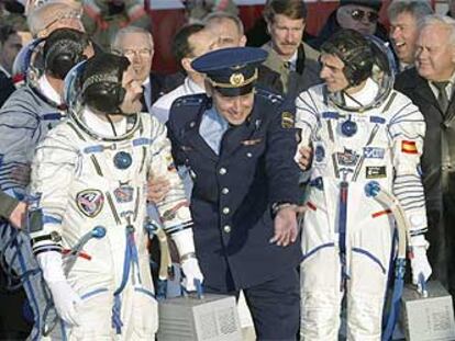 Un oficial ruso invita a Duque (derecha) y a Alexander Kareli a entrar en la nave Soyuz. El tercer astronauta, Michael Foale, aparece tapado a la izquierda.