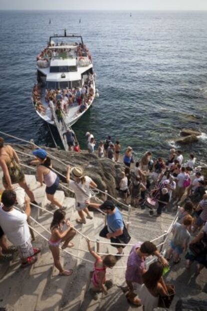 Decenas de turistas suben al barco que enlaza los pueblos del parque de Cinque Terre.