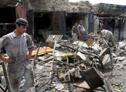 Varias personas observan los restos de los locales afectados por la explosión del coche bomba en Bagdad.